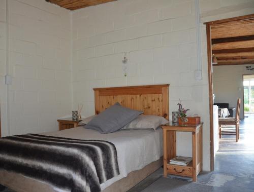 Schlafzimmer mit einem Bett mit einem Kopfteil aus Holz in der Unterkunft Bibi's Joy in Swellendam