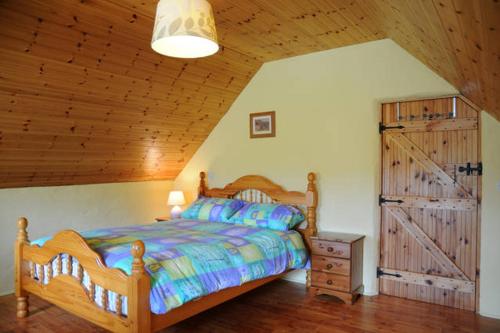 a bedroom with a bed and a wooden ceiling at Griffins Holiday Cottage in Dingle