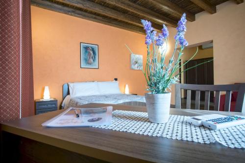 una mesa con un libro y un jarrón con flores. en L'Arco dei Sogni, en Malvagna
