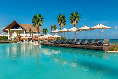 a pool at a resort with chairs and umbrellas at El Beso Adults Only at Ocean Riviera Paradise All Inclusive in Playa del Carmen
