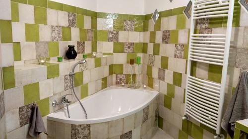 a bath tub in a bathroom with green and white tiles at Casa Pablo in Badalucco