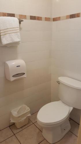 a bathroom with a toilet and a paper dispenser on the wall at Hotel La Colonia in Retalhuleu