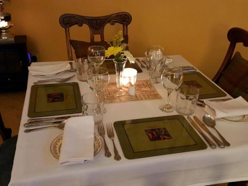 a table with a white table cloth with plates and wine glasses at Lowther House in Pickering