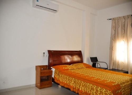 a bedroom with a bed and a table and a window at Guest House Lumen in Lomé