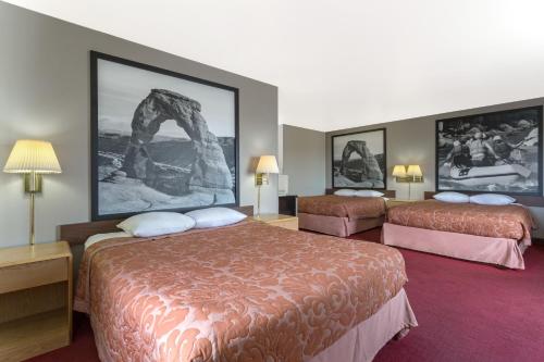a hotel room with two beds and pictures on the wall at Super 8 by Wyndham Green River in Green River