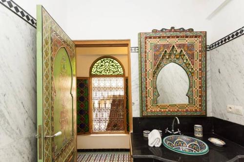 a bathroom with a sink and a mirror and a door at Riad Vega in Fès