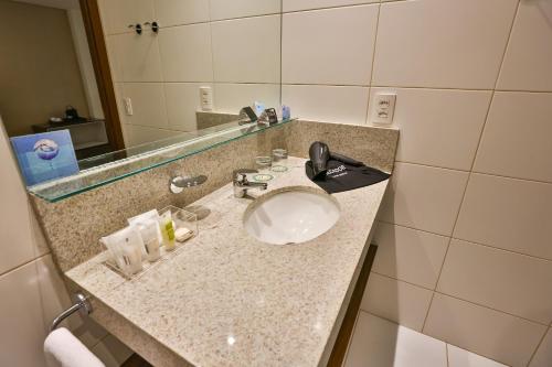 a bathroom counter with a sink and a mirror at Quality Hotel Flamboyant in Goiânia