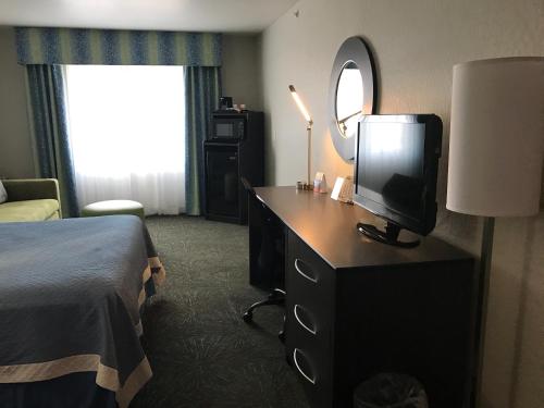 a hotel room with a bed and a television on a dresser at Days Inn & Suites by Wyndham East Flagstaff in Flagstaff