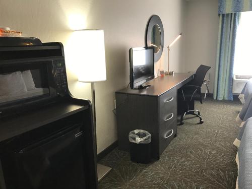 a hotel room with a desk with a tv and a mirror at Days Inn & Suites by Wyndham East Flagstaff in Flagstaff