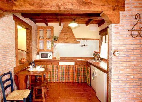 a small kitchen with a table and a table and a counter at Casa Rural La Riba in Sames