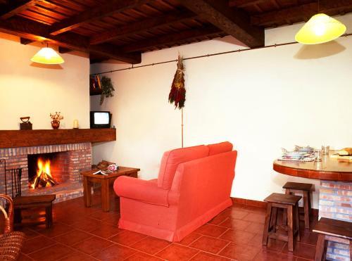 a living room with a red chair and a fireplace at Casa Rural La Riba in Sames
