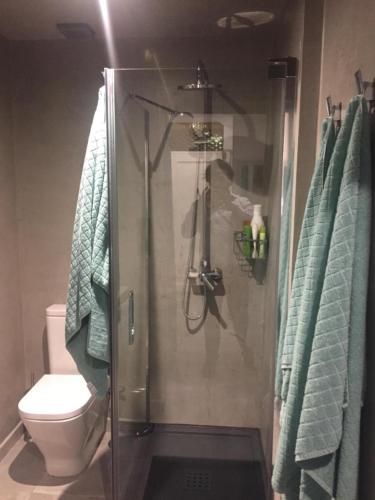a bathroom with a shower with a toilet and towels at Piso con piscina y garaje en la Playa de Las Canteras in Las Palmas de Gran Canaria