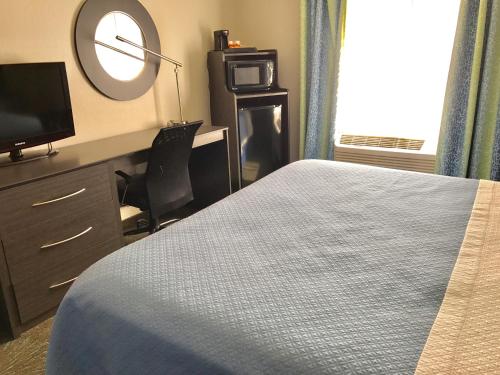 a bedroom with a bed and a desk and a mirror at Days Inn & Suites by Wyndham East Flagstaff in Flagstaff