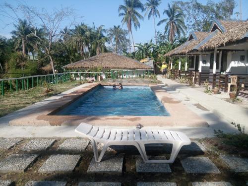 - une piscine avec un banc en face d'une maison dans l'établissement Dahilig Resort, à Puerto Galera