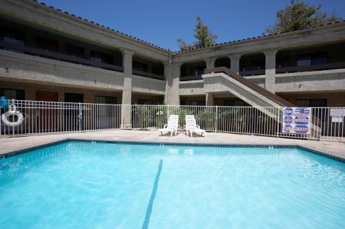 a swimming pool in front of a building with two chairs at Premier Inns Thousand Oaks in Thousand Oaks