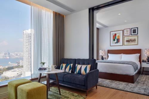 a hotel room with a bed and a chair and a large window at Little Tai Hang in Hong Kong