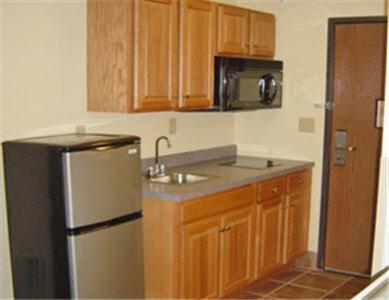 a kitchen with a stainless steel refrigerator and wooden cabinets at Hometown Inn & Suites in Schererville