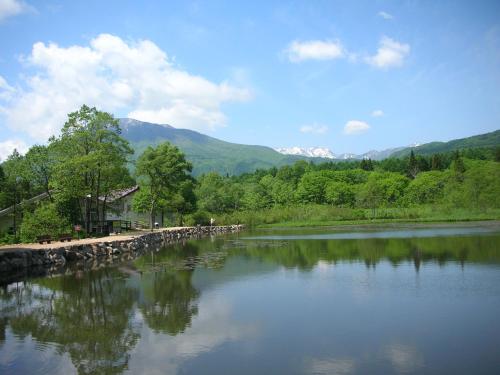 a river with trees and mountains in the background at Pension Moomin Papa in Myoko