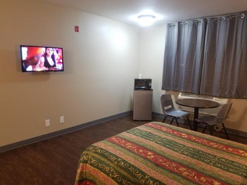 Habitación de hotel con cama y TV en la pared en Travel Time Motel, en San Diego