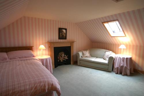 a bedroom with a bed and a chair and a fireplace at Springburn Cottage in Strachur