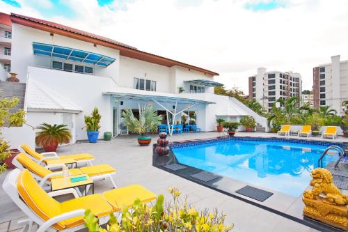 une piscine avec des chaises jaunes et un bâtiment dans l'établissement Sharrow Bay, à Pattaya (sud)