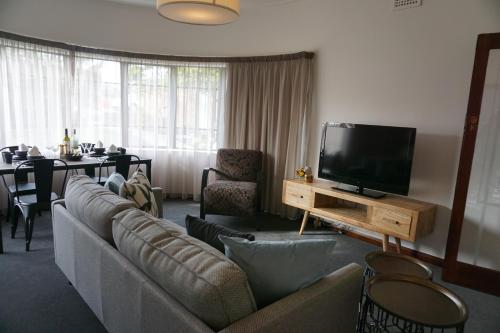 sala de estar con sofá y TV de pantalla plana en Southlynne, en Launceston