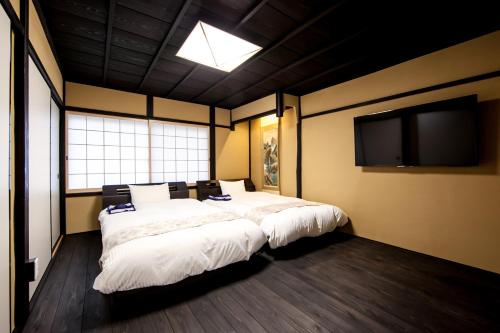 a bedroom with two beds and a flat screen tv at Miro Kyoto Shichjo Hanabatakecho Tei in Kyoto