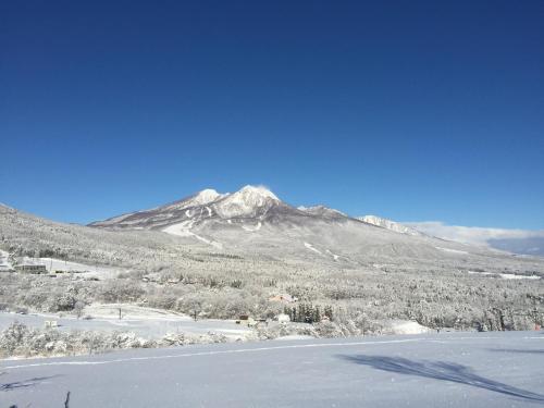 a snow covered mountain in the distance with a lake at Pension Moomin Papa in Myoko