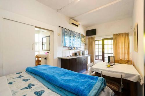 a bedroom with a large blue bed and a kitchen at Villa Valencia in Pinetown