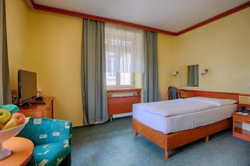 ein Hotelzimmer mit einem Bett und einem TV in der Unterkunft Ensana Vila Trajan in Piešťany