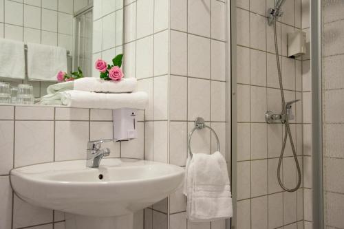 uma casa de banho com um lavatório e um chuveiro com toalhas em astral'Inn Leipzig Hotel & Restaurant em Leipzig