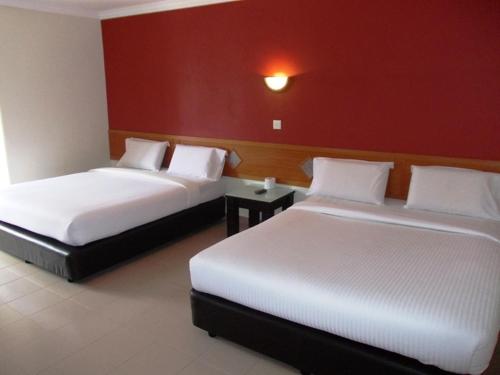 Lotus Hotel Johor Bahru في جوهور باهرو: سريرين في غرفة ذات جدار احمر