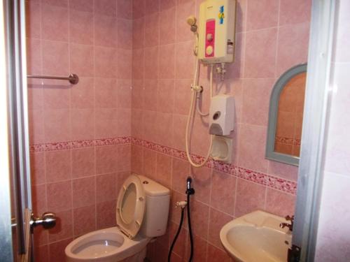 une salle de bains rose avec toilettes et lavabo. dans l'établissement Lotus Hotel Johor Bahru, à Johor Bahru