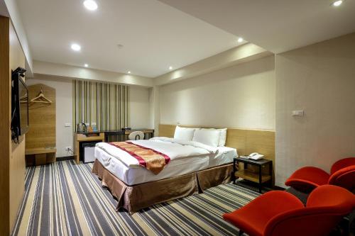 Habitación de hotel con cama y sillas rojas en Country Garden Hotel en Chiayi