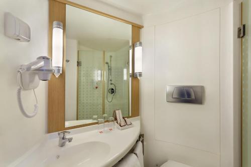 a bathroom with a sink and a shower and a mirror at ibis Yogyakarta Adi Sucipto in Yogyakarta