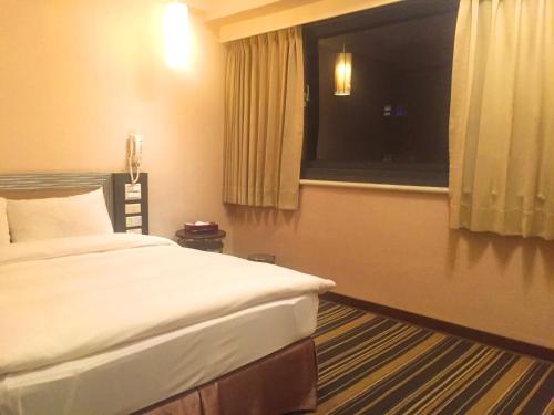 a hotel room with a bed and a window at Country Garden Hotel in Chiayi City