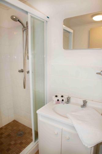 a white bathroom with a shower and a sink at Altitude 1260 in Crackenback