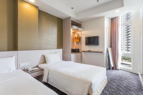 a hotel room with two beds and a tv at Scott Hotel KL Sentral in Kuala Lumpur