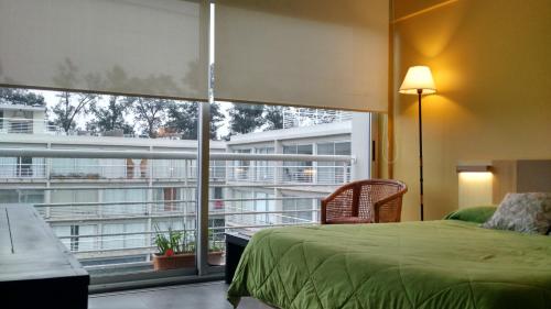 a bedroom with a green bed and a large window at CONCORD PILAR"313 Almendros"50m2 en Suite -living y dormitorio- de 1 a 4 huéspedes in Pilar