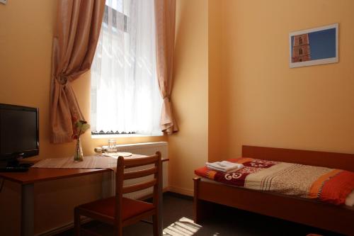 a bedroom with a desk and a bed and a window at Penzion Česká Koruna in Čáslav