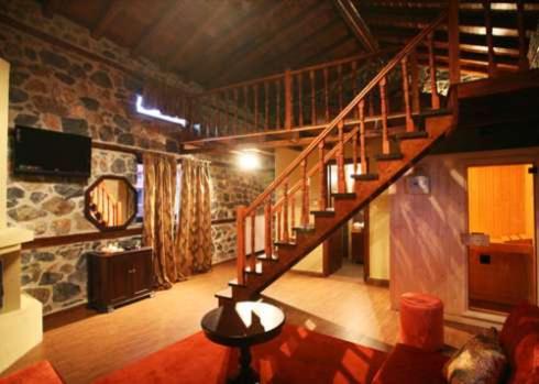 a living room with a staircase in a stone building at Gioras Hotel in Palaios Agios Athanasios