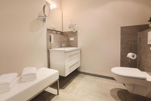 a bathroom with a toilet, sink, and bathtub at Romantik Hotel am Brühl in Quedlinburg