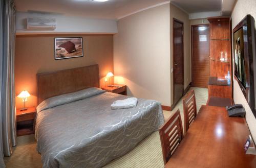 a hotel room with a bed and two tables and two lamps at Voyage Hotel in Almaty