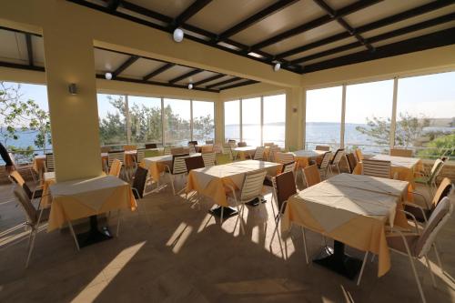 ein Restaurant mit Tischen, Stühlen und Fenstern in der Unterkunft Hotel Vila 4m in Ražanac