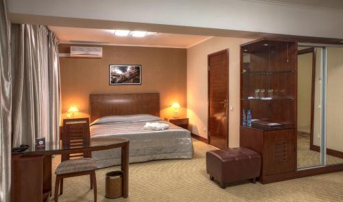 a bedroom with a bed and a desk and a table at Voyage Hotel in Almaty