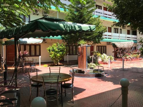 a patio with a table and chairs and a green umbrella at Gnaanams Hotel and Restaurant in Jaffna