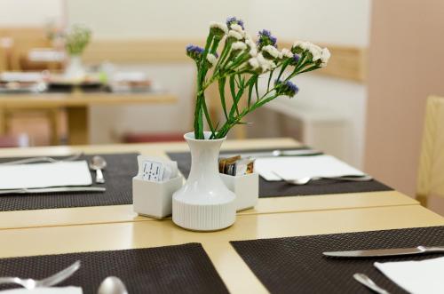 a white vase with flowers in it on a table at Hotel Garibaldi in Palermo