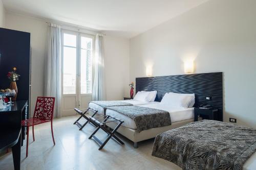 a hotel room with two beds and a table and chairs at Hotel Garibaldi in Palermo