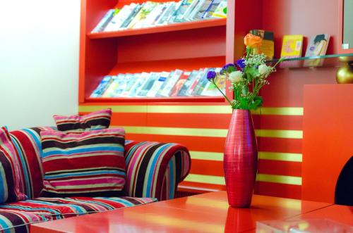 a red vase with flowers on a table next to a couch at Hotel Garibaldi in Palermo