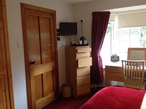 1 dormitorio con cama, puerta y ventana en Dunroamin Bed and Breakfast, en Aviemore